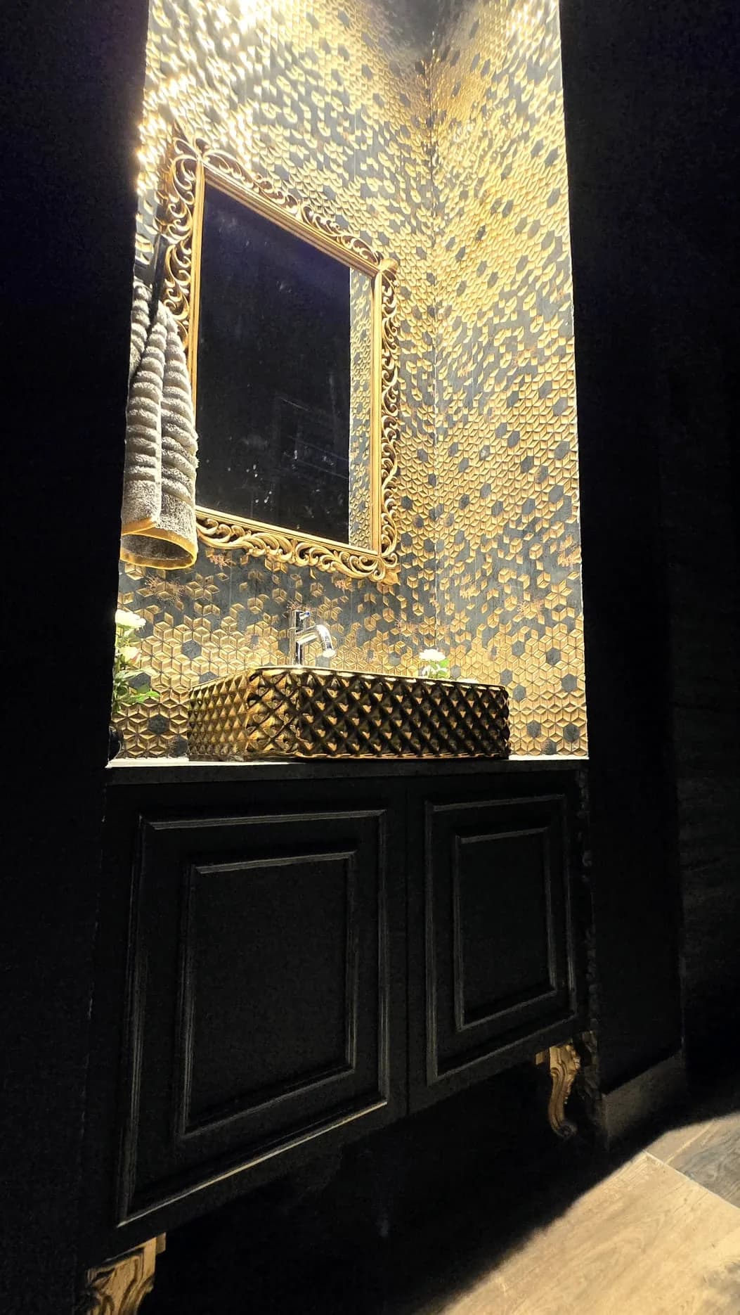 Ornate gold-framed mirror above a designer washbasin